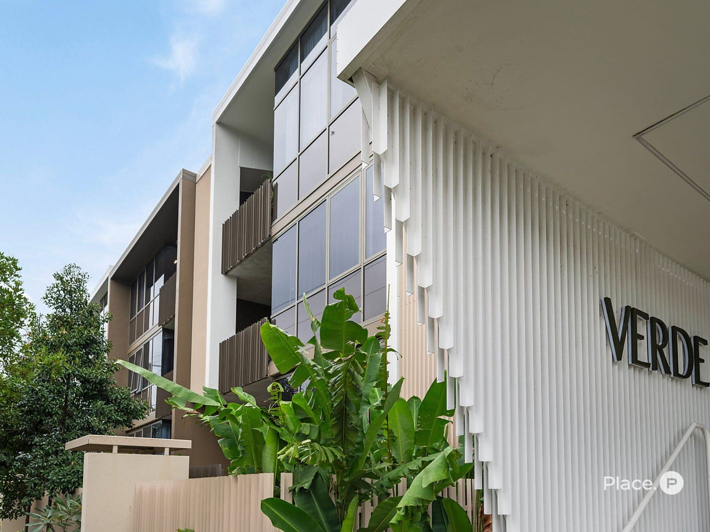 Verde — white slatted facade with VERDE signage and subtropical planting